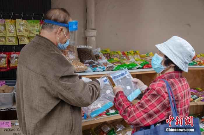 当地时间5月18日,一位老人在美国旧金山华埠一处店铺外的摊位前购买防疫物品。中新社记者 刘关关 摄 调查:四分之一美国民众对接种新冠疫苗心存顾忌